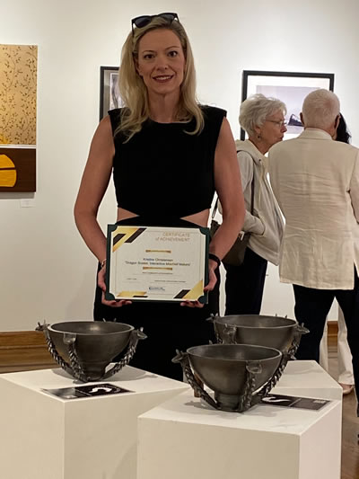 Kristine holding a 2nd place certificate for a community art show